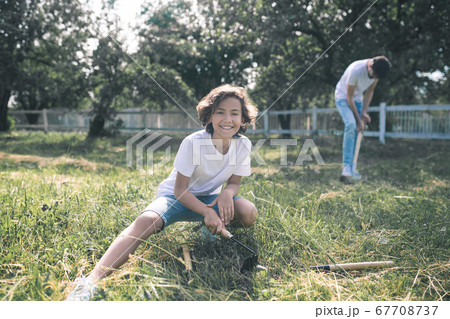 Dark-haired boy sitting on the grass and smiling while his dad digging 67708737