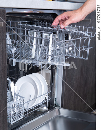 Housework open dishwasher and man putting a glass in the machine Housework open dishwasher and man putting a glass in the machine 67708757