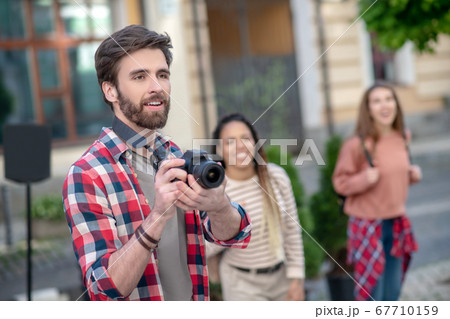 Young adult guy holding camera and two funny girls Young adult guy holding camera and two funny girls 67710159