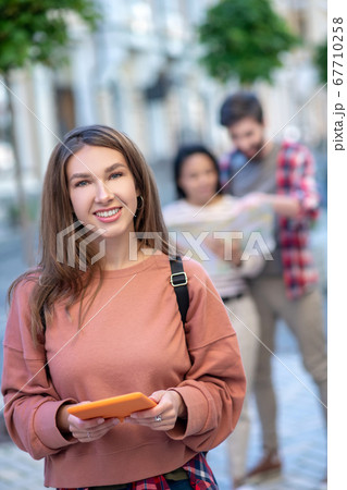 Cute girl with tablet in the hands, friends at distance 67710258