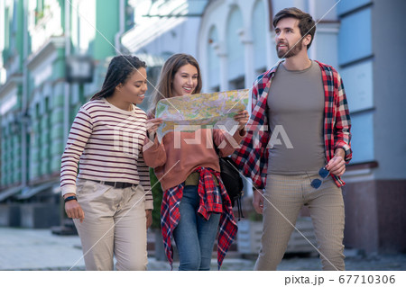 Bearded guy and girls with map walking down street Bearded guy and girls with map walking down street 67710306
