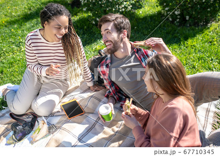 Young and happy friends having a picnic on the lawn 67710345