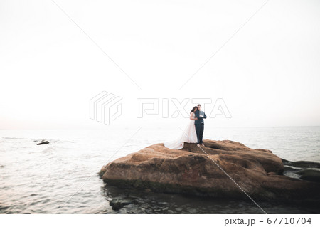 Wedding couple, groom, bride with bouquet posing near sea and blue sky 67710704