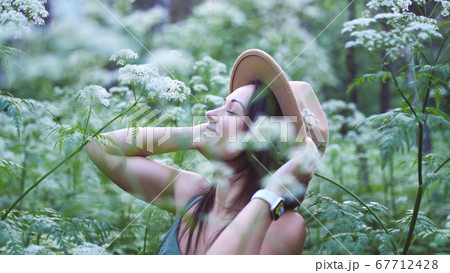 Young pretty woman in hat poses in deep forest among white flowers. Young pretty woman in hat poses in deep forest among white flowers. 67712428