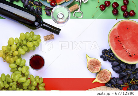 A bottle of wine, wineglass, grapes, different fruits and the flag of Italy. Country symbol backdrop A bottle of wine, wineglass, grapes, different fruits and the flag of Italy. Country symbol backdrop 67712890