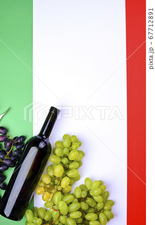 A bottle of wine, grapes, and the flag of Italy close-up. Country symbol backdrop. The concept of A bottle of wine, grapes, and the flag of Italy close-up. Country symbol backdrop. The concept of 67712891