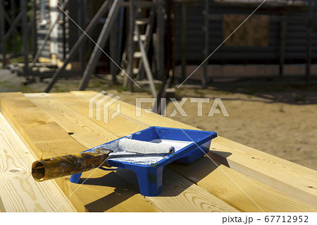 Paint bath with paint roller and white paint on unpainted pine boards 67712952