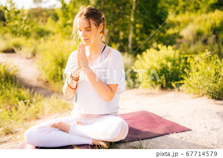 Attractive young woman is meditating and doing breathing exercising sitting in pose of lotus Attractive young woman is meditating and doing breathing exercising sitting in pose of lotus 67714579