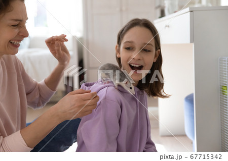Overjoyed mother and teenage daughter playing with cute rat 67715342