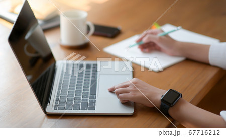 The hand of a young woman using a laptop and The hand of a young woman using a laptop and 67716212