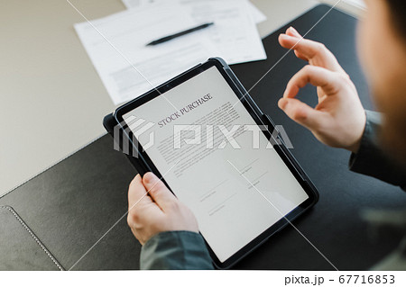 Man reading stock purchase agreement on tablet and showing ok gesture. Man reading stock purchase agreement on tablet and showing ok gesture. 67716853