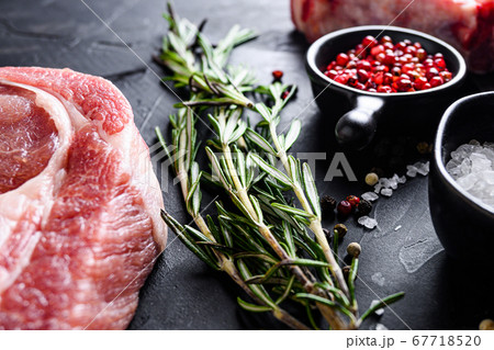 Rosemary herbs close up on black stone table with spices and raw meat near side view selective focus Rosemary herbs close up on black stone table with spices and raw meat near side view selective focus 67718520