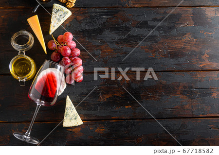 molded cheeses and snacks red wine glass honey grapes on old vintage dark wooden table Top view. Free space for text. molded cheeses and snacks red wine glass honey grapes on old vintage dark wooden table Top view. Free space for text. 67718582