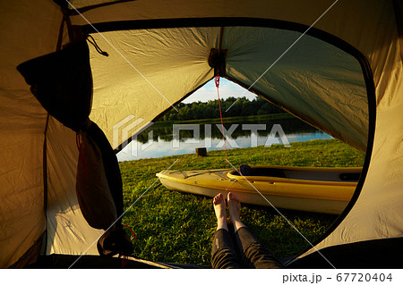 Feet of young women relaxing with lake view from tent camping entrance outdoor. Travel wanderlust lifestyle concept adventure vacations outdoor, Summer holiday and vacation trip. 67720404