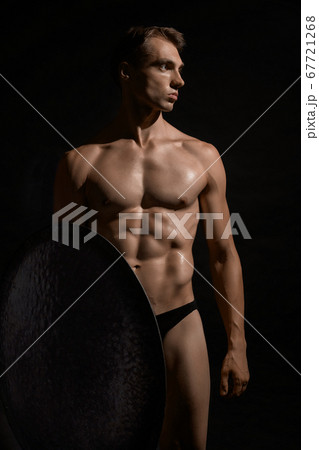 Young warrior with shield isolated on black. 67721268