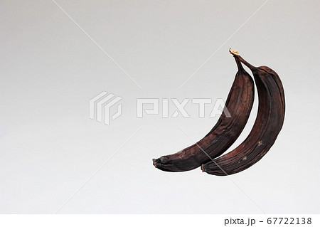 Spoiled old bananas. Two rotten blackened and  dried bananas . Spoiled food.  67722138