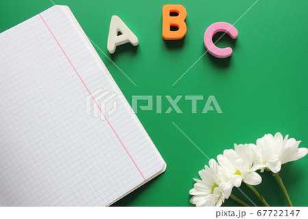 School notebook next to the letters ABC and white chrysanthemums on a green background. School notebook next to the letters ABC and white chrysanthemums on a green background. 67722147