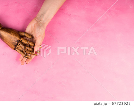White female hand holding black wooden hand White female hand holding black wooden hand 67723925
