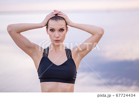 portrait of a beautiful fitness model on a background of the sea at sunset portrait of a beautiful fitness model on a background of the sea at sunset 67724434