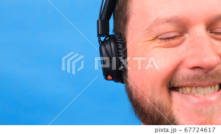 Cheerful charismatic fat man in headphones isolated and pink t-shirt on a blue background. listen to 67724617