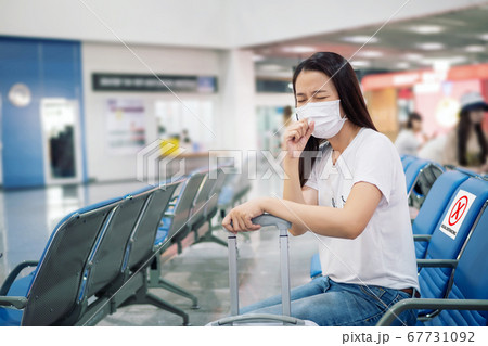Asian tourist feeling sick, coughing ,wearing mask and sit on chair with social distancing to prevent pandemic during travel at airport terminal. new normal after coronavirus, covid-19 virus epidemic Asian tourist feeling sick, coughing ,wearing mask and sit on chair with social distancing to prevent pandemic during travel at airport terminal. new normal after coronavirus, covid-19 virus epidemic 67731092