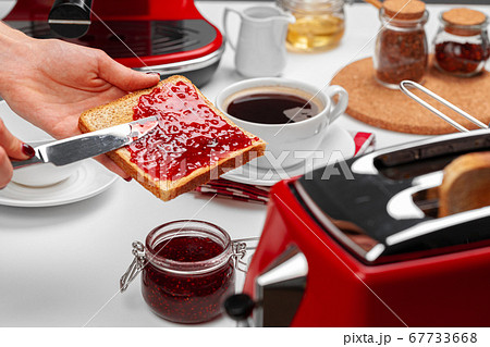 Female hand spresding strawberry jam on baked toast Female hand spresding strawberry jam on baked toast 67733668