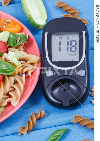 Glucometer with sugar level and salad with pasta and vegetables 67734798