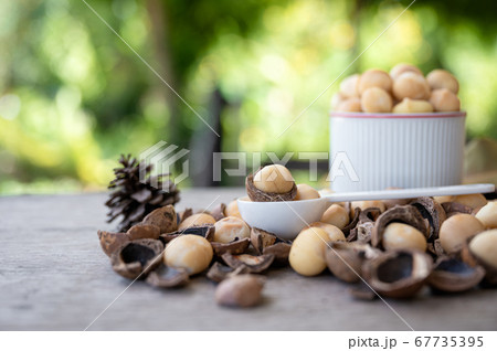 Organic Macadamia nuts with shell in spoon on wood Organic Macadamia nuts with shell in spoon on wood 67735395
