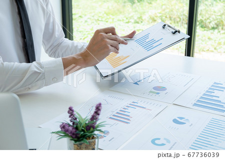 business man is sitting at a desk and calculating financial graph that show results In the office business man is sitting at a desk and calculating financial graph that show results In the office 67736039