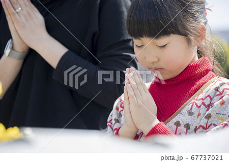 お墓参りをする母親と小学生娘 お墓参りをする母親と小学生娘 67737021
