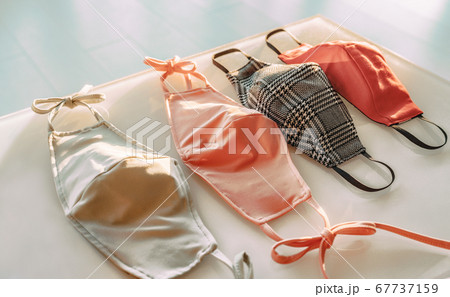 Many fabric face masks for sale at fashion designer store selling clothing and cloth mask made for COVID-19 prevention on shop shelf. Wearing a polyester or cotton mouth covering against coronavirus 67737159