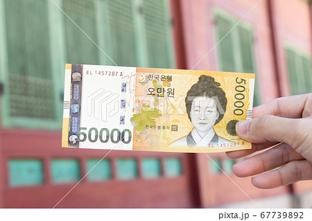 Traveller hand hold 50000 korean won banknote on defocused Korean palace background. 67739892