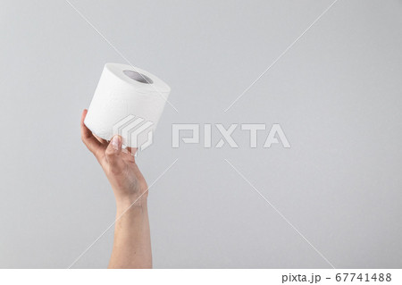 Female hand holds a soft roll of toilet paper on a gray background with copy space. Composition for advertising, article or banner Female hand holds a soft roll of toilet paper on a gray background with copy space. Composition for advertising, article or banner 67741488