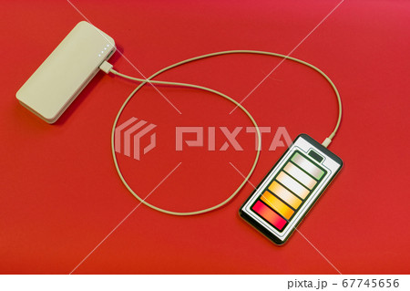 Smartphone is charging with power bank on red 67745656