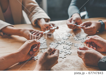 Business team handle a piece of white puzzles that Business team handle a piece of white puzzles that 67747843