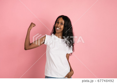 Cheerful african-american young woman isolated on pink background, emotional and expressive 67748492