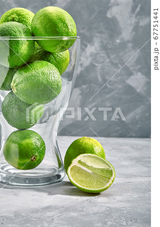 glass vase full of green limes on concrete background glass vase full of green limes on concrete background 67751441
