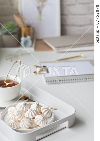 Work table near the window in the Scandinavian Nordic style. Female work and home office concept. White and gold office. Flowers in a vase and rings, bracelets on the table. Work table near the window in the Scandinavian Nordic style. Female work and home office concept. White and gold office. Flowers in a vase and rings, bracelets on the table. 67752878