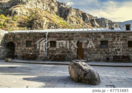 Geghard monastery in Armenia with a sacred stone in the courtyard and benches for pilgrims next to the room for priests Geghard monastery in Armenia with a sacred stone in the courtyard and benches for pilgrims next to the room for priests 67753885