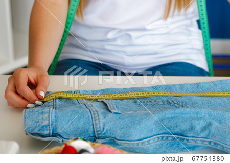 Woman tailor making measurements with measuring tape in her office 67754380