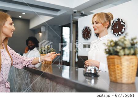 Blonde woman hotel guest checking-in at front desk in hotel 67755061