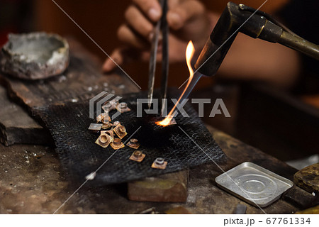 A person is melting silver to make jewellery. 67761334