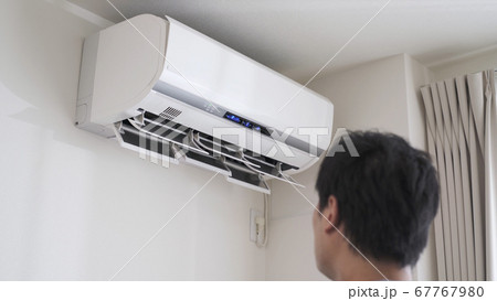 エアコンの電源をつける男性 67767980