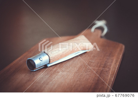 Wooden cutting board and pocket knife on a black Wooden cutting board and pocket knife on a black 67769076