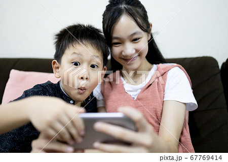 Excited kid boy and child girl are enjoying playing online game on mobile phone,siblings having fun relaxing together,children sister and brother using smartphone to watch cartoon video,stay home 67769414