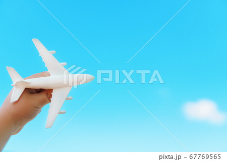 A white airplane in a child's hand against a blue A white airplane in a child's hand against a blue 67769565