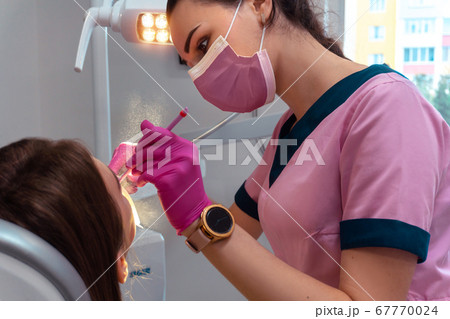 dentist in pink uniform treat the teeth of a patient dentist in pink uniform treat the teeth of a patient 67770024