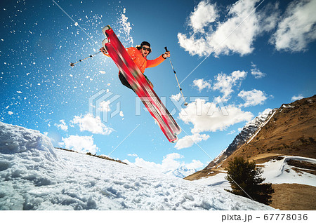 Jump with a trick in the ozdou athlete skier with a kicker on a sunny day of spring or winter against the blue sky and sun Jump with a trick in the ozdou athlete skier with a kicker on a sunny day of spring or winter against the blue sky and sun 67778036