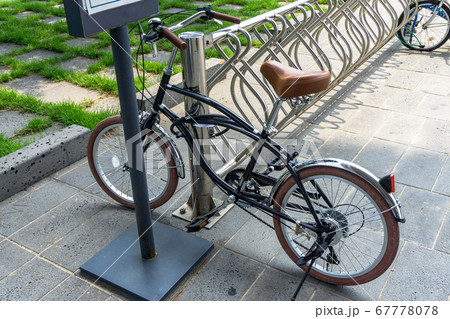 Glossy black vintage bicycle parks at the bicycle park with anti-theft bike lock cable hook up to the stainless bar 67778078