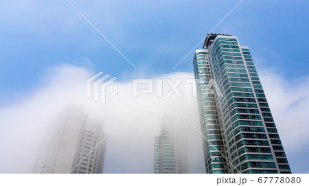 Thick large and heavy mist blow and pass through skyscrapers and cover all other buildings in the area 67778080